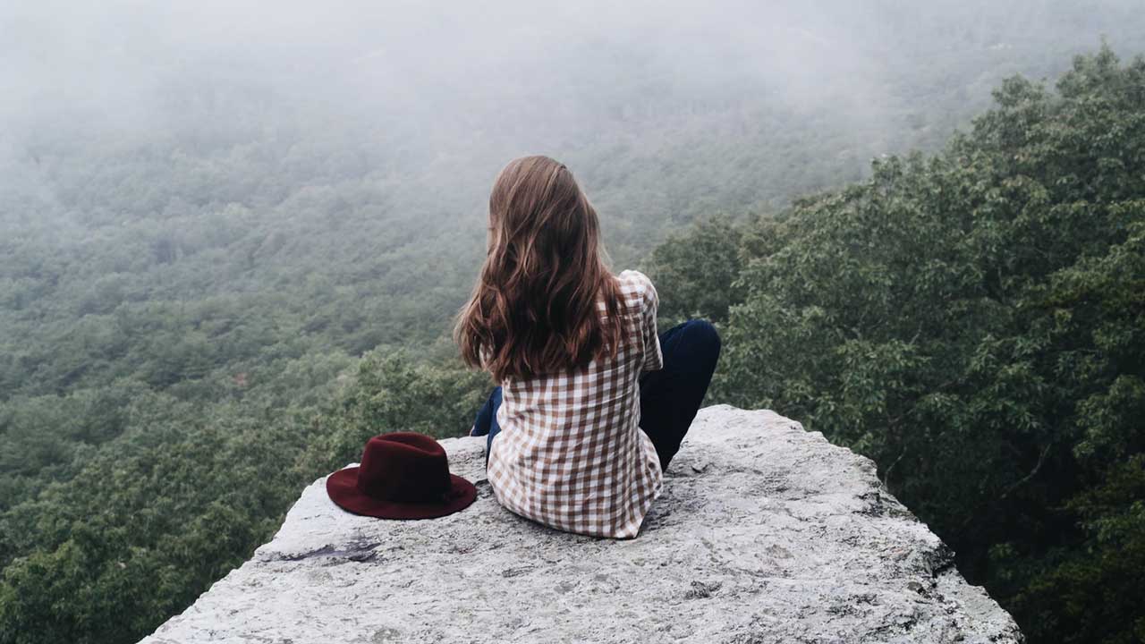 girl alone sitting on a rock